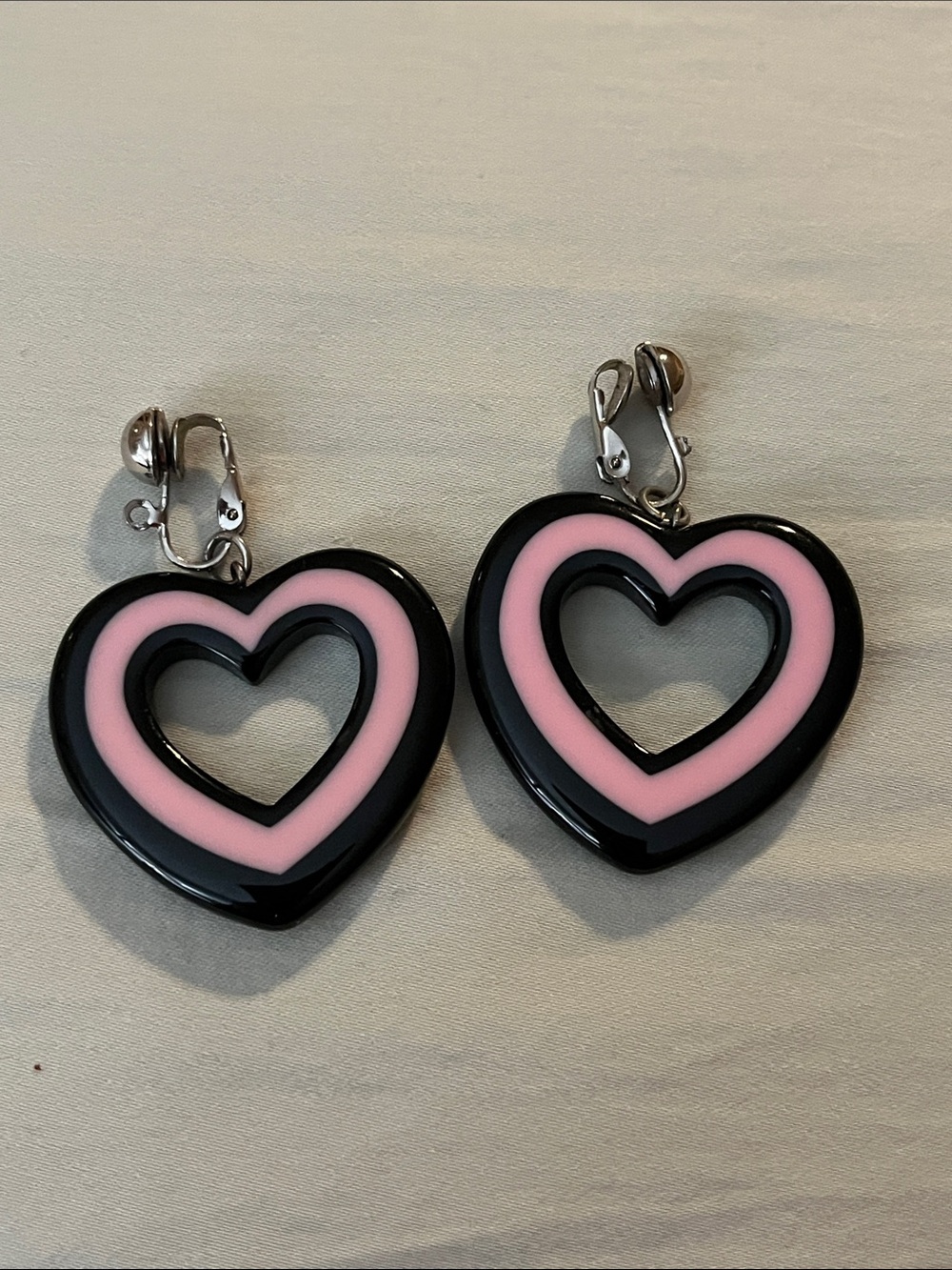 Vintage pair of pink and black heart-shaped clip-on earrings.